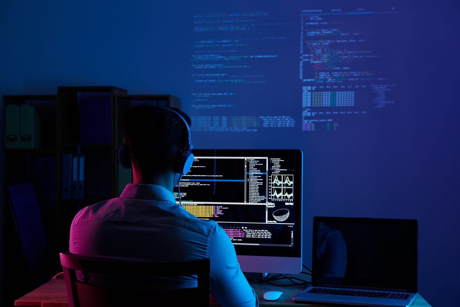 Programer radi na kodu kasno noću, pogled s leđa